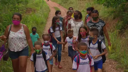 Sem ônibus escolar, crianças caminham mais de 30 minutos no meio do barro para poder estudar
